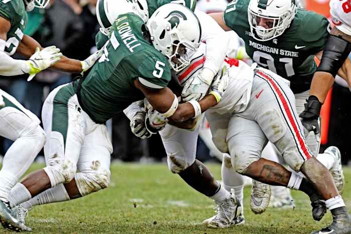 Michigan State's Andrew Dowell, left, tackles Ohio State's Mike Weber Jr. © Nick King/Lansing State Journal